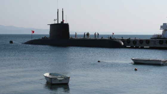 A submarine is visible in the water next to a small row boat